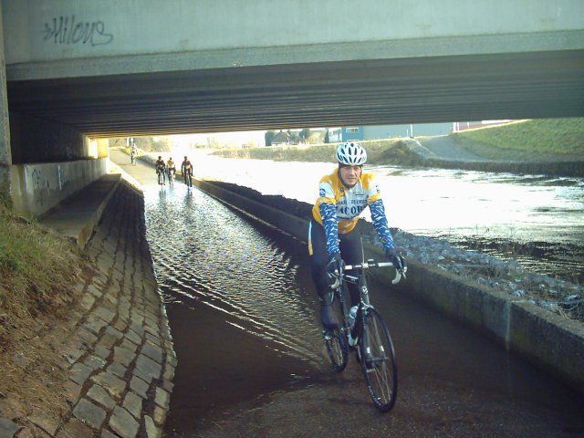 Stoof is Titanic
Onder de brug van de Ring van Aarschot over de Demer was er ook wat wateroverlast. Een oudere wielertoerist reed om langs het ronde punt om deze gevarenzone te mijden. Wij zijn echter echte mannen. Stoof gaat ervoor, duikt het ijskoude water in en geraakt er in een moeite door.
