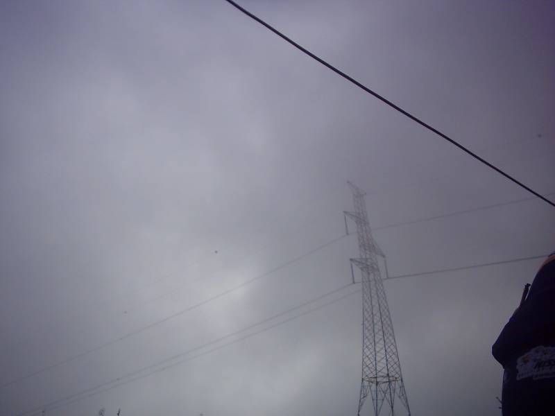 Laaghangende wolken
Het was maar een frisse ochtend - Danny had zelfs zijn mouwkes aan - en er was een dicht laaghangend wolkendek. De pylonen en ook de windmolens die we net gepasseerd waren, stond met hun kop in de wolen. Maar het bleef wel droog, en later zou de zon er nog doorkomen.
